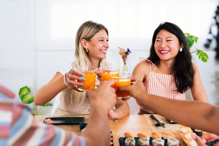 Multiethnic group of young friends meeting at home and eating sushi - Multiracial happy people bonding while having lunchの写真素材