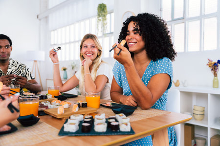 Multiethnic group of young friends meeting at home and eating sushi - Multiracial happy people bonding while having lunchの写真素材