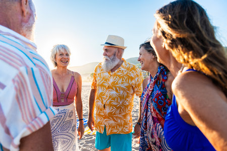 Happy group of senior friends bonding at the beach during summertime - Cheerful old and mature people having fun at the sea on summer vacation, elderly lifestyle conceptsの写真素材
