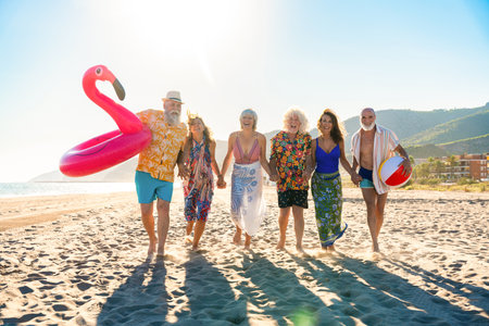 Happy group of senior friends bonding at the beach during summertime - Cheerful old and mature people having fun at the sea on summer vacation, elderly lifestyle conceptsの写真素材