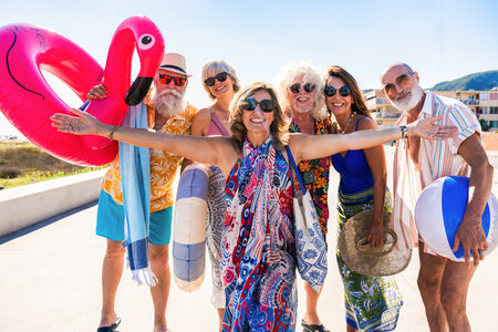 Happy group of senior friends bonding at the beach during summertime - Cheerful old and mature...