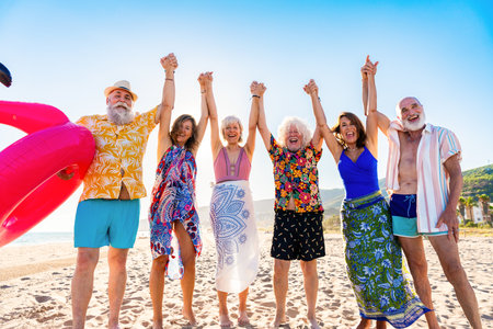 Happy group of senior friends bonding at the beach during summertime - Cheerful old and mature people having fun at the sea on summer vacation, elderly lifestyle conceptsの写真素材