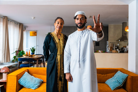 Happy beautiful young arab couple with emirati clothing together at home - Middle-eastern man and...