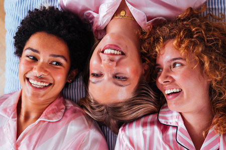 Multiethnic group of young female friends having pajamas party at home - Happy cheerful best girlfriends bonding and having fun at homeの写真素材