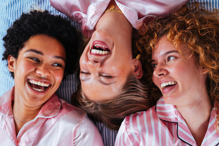 Multiethnic group of young female friends having pajamas party at home - Happy cheerful best girlfriends bonding and having fun at homeの写真素材