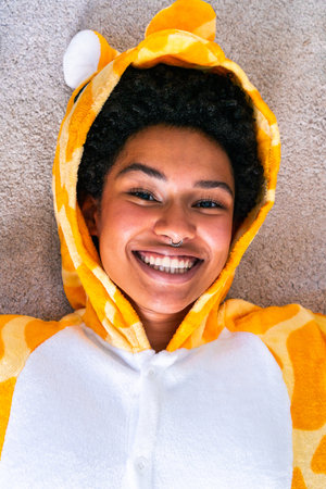 Portrait of beautiful black young woman wearing funny giraffe pajama costume at home - Happy cheerful best girlfriends bonding and having funの写真素材