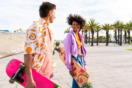 Young multiethnic modern couple with skateboards dating outdoors - Two friends having fun skating around city urban areas, concepts about youth, diversity, green transportation and mobilityの写真素材