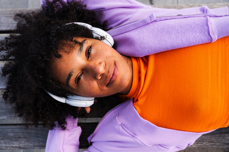 Beautiful young black woman with curly afro hair portrait outdoors - Modern cool stylish female wearing urban clothingの写真素材