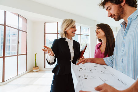 Real estate agent showing a new apartment and features of a good investment to a young couple. Woman and man buying a property in a rich area of the city.の写真素材