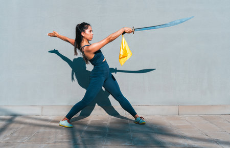 Chinese young woman practicing wushu kung fu with weapons outdoor. Young girl training martial arts form for the competition.の写真素材