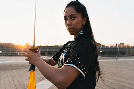 Chinese young woman practicing wushu kung fu with weapons outdoor. Young girl training martial arts form for the competition.の写真素材