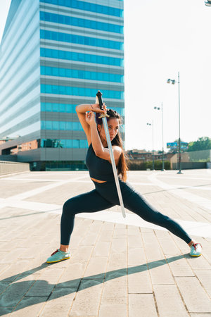 Chinese young woman practicing wushu kung fu with weapons outdoor. Young girl training martial arts form for the competition.の写真素材
