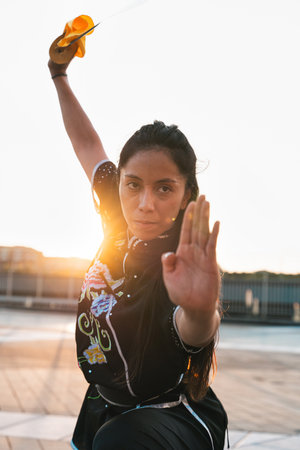 Chinese young woman practicing wushu kung fu with weapons outdoor. Young girl training martial arts form for the competition.の写真素材