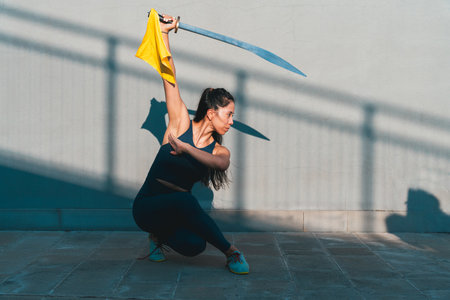 Chinese young woman practicing wushu kung fu with weapons outdoor. Young girl training martial arts form for the competition.の写真素材