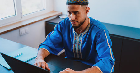 Moroccan Business man in the office. Young business man with traditional outfit working in his...