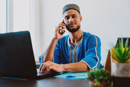 Moroccan Business man in the office. Young business man with traditional outfit working in his office.の写真素材