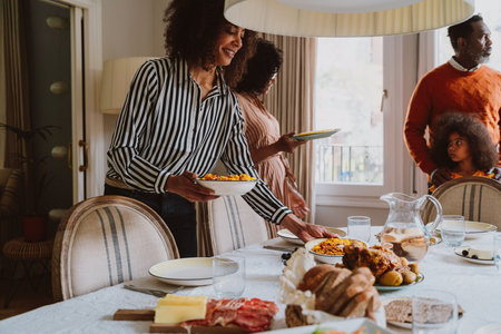 Storytelling image of a Family reunited at parents house for lunch on the holidays. Family members celebrating at home eating good food, sharing love and positive emotions.の写真素材