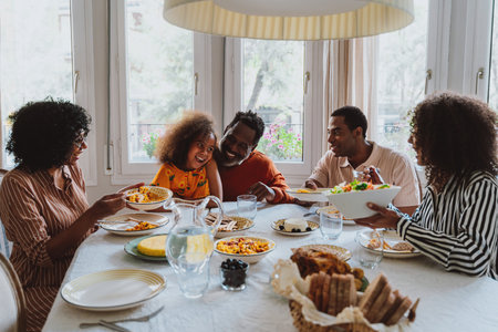 Storytelling image of a Family reunited at parents house for lunch on the holidays. Family members celebrating at home eating good food, sharing love and positive emotions.の写真素材