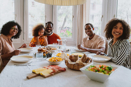 Storytelling image of a Family reunited at parents house for lunch on the holidays. Family members celebrating at home eating good food, sharing love and positive emotions.の写真素材