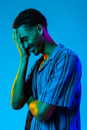 African man young portrait in studio on colorful background - Cool black young male with stylish attire posing, creative colored lightingの写真素材