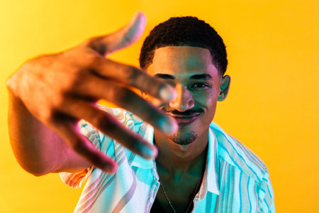 African young man portrait in studio on colorful background - Cool black young male with stylish attire posing, creative colored lightingの写真素材