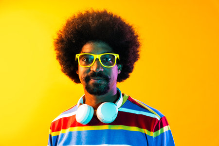 African man portrait in studio on colorful background - Cool black young male with stylish attire posing, creative colored lightingの写真素材