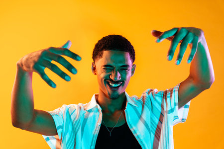 African young man portrait in studio on colorful background - Cool black young male with stylish attire posing, creative colored lightingの写真素材