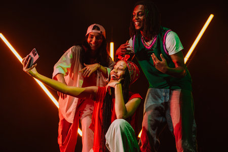 Group of hip hop dancers dancing together in a moody studio with tube neon lights. Taking selfies...