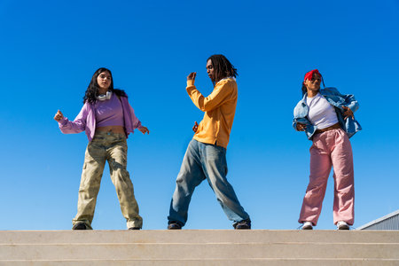Young group of multiethnic hip-hop dancers wearing colorful urban streetwear dancing - Stylish multiracial rap crew portrait in the cityの写真素材