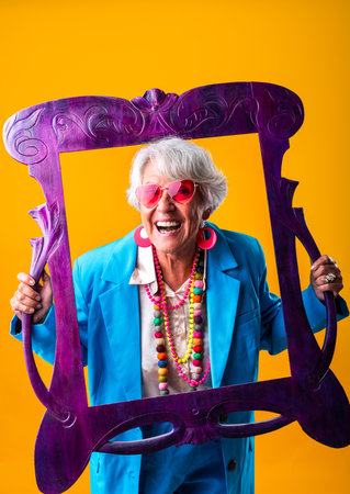Beautiful senior woman with gray hair wearing colorful stylish clothing portrait in studio - Cheerful old grandmother with fashionable styleの写真素材