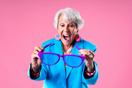 Beautiful senior woman with gray hair wearing colorful stylish clothing portrait in studio - Cheerful old grandmother with fashionable styleの写真素材