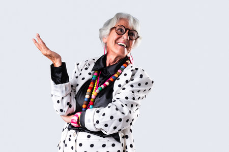Beautiful senior woman with gray hair wearing colorful stylish clothing portrait in studio - Cheerful old grandmother with fashionable styleの写真素材