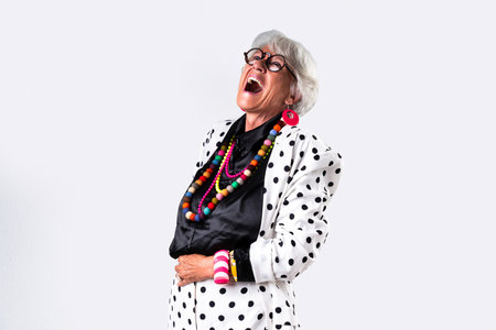 Beautiful senior woman with gray hair wearing colorful stylish clothing portrait in studio - Cheerful old grandmother with fashionable styleの写真素材
