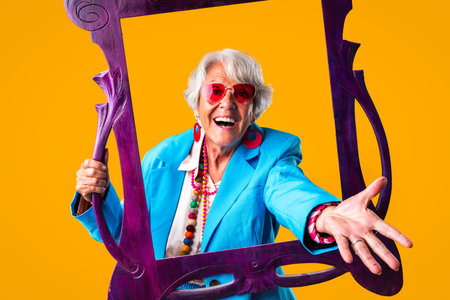 Beautiful senior woman with gray hair wearing colorful stylish clothing portrait in studio - Cheerful old grandmother with fashionable styleの写真素材