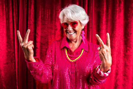 Beautiful senior woman with gray hair wearing colorful stylish clothing portrait in studio - Cheerful old grandmother with fashionable styleの写真素材