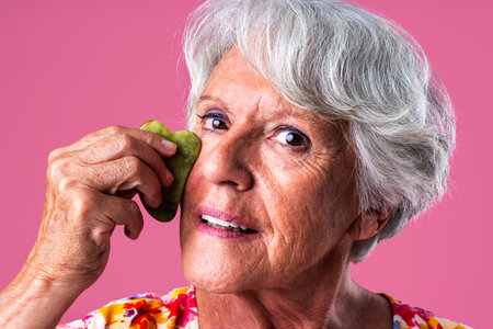 Senior woman with gray hair wearing colorful stylish clothing portrait in studio - Cheerful grandmother doing beauty treatment for skin careの写真素材