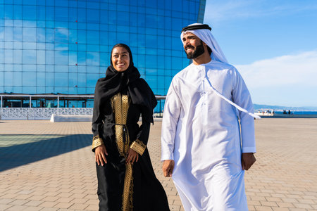 Traditional arab couple wearing emirati clothing outdoors - Middle-eastern married woman with abaya...