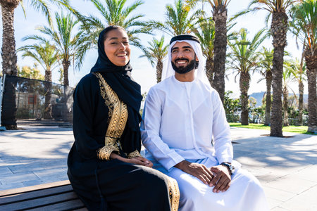 Traditional arab couple wearing emirati clothing outdoors - Middle-eastern woman with abaya and man...