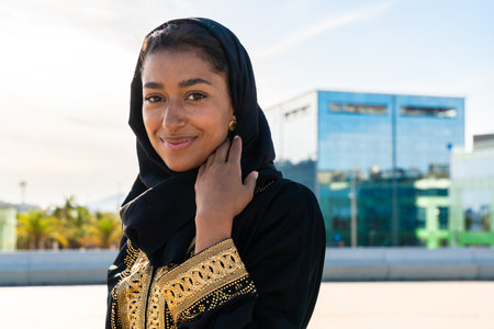 Traditional arab woman wearing emirates abaya outdoors - Beautiful middle-eastern adult female portrait in the cityの写真素材