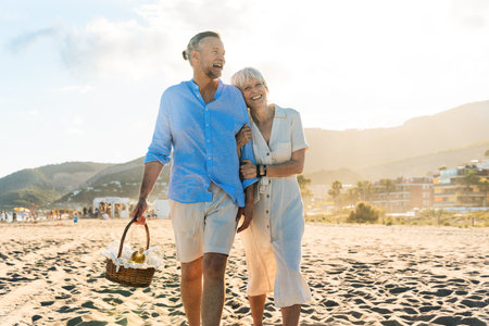 Beautiful happy senior couple dating at the seaside during summertime - Mature married couple in love bonding outdoors at the beach, concepts about elderly lifestyle, relationship and quality of lifeの写真素材