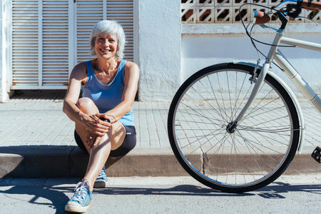 Beautiful happy senior woman cycling during summertime - Mature adult female with gray hair riding bicycle, concepts about elderly lifestyle, transportation and quality of lifeの写真素材