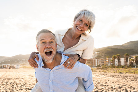 Beautiful happy senior couple dating at the seaside during summertime - Mature married couple in love bonding outdoors at the beach, concepts about elderly lifestyle, relationship and quality of lifeの写真素材
