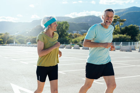 Beautiful happy senior couple running outdoors - Mature married couple in love bonding outdoors and doing sport together, concepts about elderly lifestyle, relationship and quality of lifeの写真素材