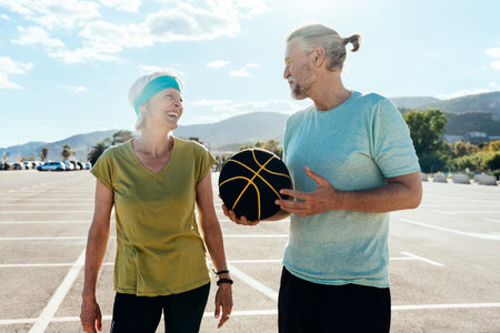 Senior couple playing basketball outdoors, concepts about elderly lifestyle, aging and sportの写真素材