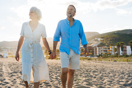 Beautiful happy senior couple at the seaside during summertime - Mature married couple in love bonding outdoors at the beach, concepts about elderly lifestyle, relationship and quality of lifeの写真素材