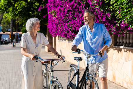 Senior couple walking with bicycle outdoors, concepts about elderly lifestyle and agingの写真素材