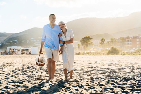 Beautiful happy senior couple dating at the seaside during summertime - Mature married couple in love bonding outdoors at the beach, concepts about elderly lifestyle, relationship and quality of lifeの写真素材