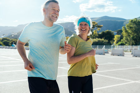 Beautiful happy senior couple running outdoors - Mature married couple in love bonding outdoors and doing sport together, concepts about elderly lifestyle, relationship and quality of lifeの写真素材