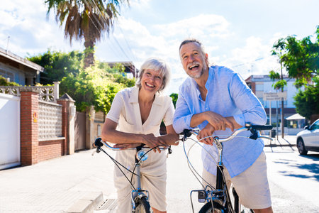 Beautiful happy senior couple dating at the seaside during summertime - Mature married couple in love bonding outdoors and riding bicycle, concepts about elderly lifestyle, transportation and quality of lifeの写真素材