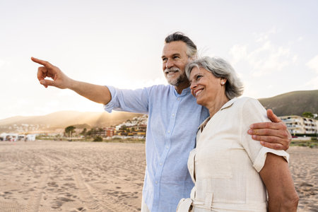 Beautiful happy senior couple dating at the seaside during summertime - Mature married couple in love bonding outdoors at the beach, concepts about elderly lifestyle, relationship and quality of lifeの写真素材